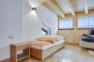 a bedroom with a bed and two windows at Ciasa Christina - Attic in Moena