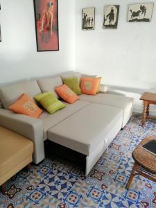 uma sala de estar com um sofá branco com almofadas laranja e verde em Beachfront House em Málaga