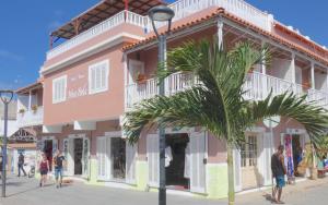 a pink building with a palm tree in front of it at Hotel MiraBela in Santa Maria