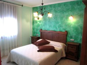 Un dormitorio con una cama con una pared verde. en Apartamentos Almagro, en Almagro