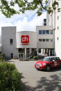 pentahotel Wiesbaden في فيسبادن: سيارة حمراء متوقفة أمام مبنى