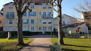 a building with two trees and a bench in a park at Résidence Dalimier #hypercentre# in Corbeil-Essonnes