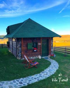 a small log cabin with a bench in the grass at Vila Mali Tornik in Zlatibor