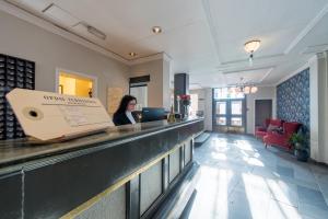 a woman standing at a counter in a hotel lobby at Oppdal Turisthotell in Oppdal