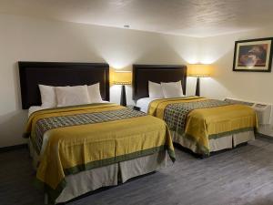 a hotel room with two beds with yellow sheets at Palomino Motel in Las Vegas