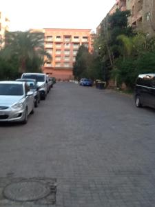 Un estacionamiento con autos estacionados frente a un edificio. en Babylon Appartments, en Marrakech