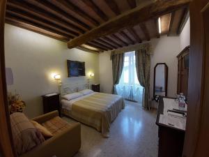 a hotel room with a bed, chair and a window at B&B Il Vecchietta in Castiglione dʼOrcia