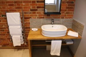 La salle de bains est pourvue d'un lavabo et d'un mur en briques. dans l'établissement Blashford Manor Farmhouse - The Shetland Cottage, à Ringwood