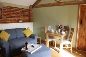 a living room with a blue couch and a table at Blashford Manor Farmhouse - The Shetland Cottage in Ringwood