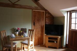 a dining room with a table and a television at Blashford Manor Farmhouse - The Shetland Cottage in Ringwood
