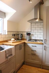 une cuisine avec des armoires blanches et un four à plaques de cuisson dans l'établissement Blashford Manor Farmhouse - The Shetland Cottage, à Ringwood 9 autres photos