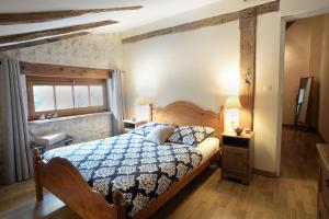 a bedroom with a bed with a blue and white comforter at Les Gîtes de La Treille in Montagrier +57 photos