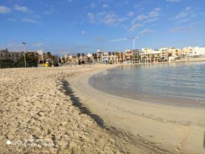 a sandy beach with buildings in the background at Arzella Holiday Home in Birżebbuġa
