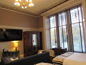 1 dormitorio con cama, sofá y ventanas en Seton Guest House, en Glasgow