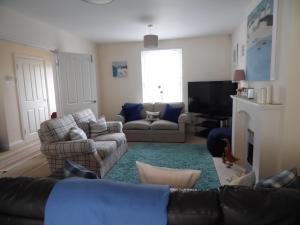 uma sala de estar com um sofá e uma televisão em Daisy Cottage em Uny Lelant