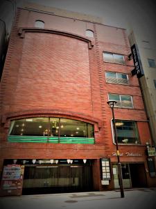 een gebouw van rode baksteen met een straatlicht ervoor bij Hotel Tokeidai in Sapporo