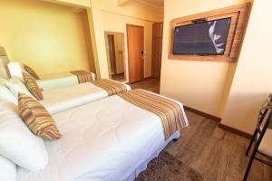 ein Hotelzimmer mit zwei Betten und einem Flachbildfernseher in der Unterkunft Hotel Alles Blau in Pelotas