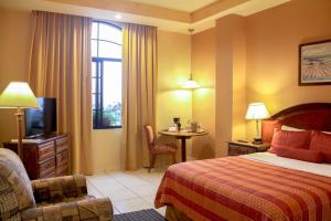 ein Hotelzimmer mit einem Bett, einem Stuhl und einem Tisch in der Unterkunft Hotel Monteolivos in San Pedro Sula