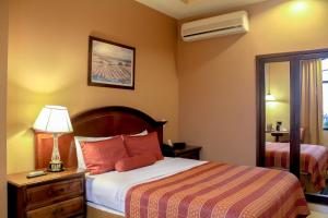 ein Hotelzimmer mit einem Bett und einer Lampe auf einem Tisch in der Unterkunft Hotel Monteolivos in San Pedro Sula