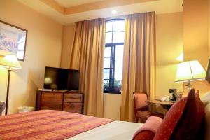 ein Hotelzimmer mit einem Bett und einem TV in der Unterkunft Hotel Monteolivos in San Pedro Sula