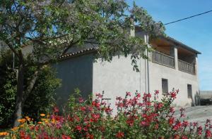 a white building with flowers in front of it at Masoveria la Roca in Sagás