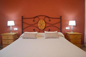 a bedroom with a large white bed with two lamps at Masoveria la Roca in Sagás +30 photos
