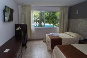 a hotel room with two beds and a window at Hotel Verdi in San Juan Bautista Tuxtepec