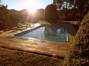 a swimming pool with chairs and the sun in the background at Pousada Sonho Verde in Monte Verde