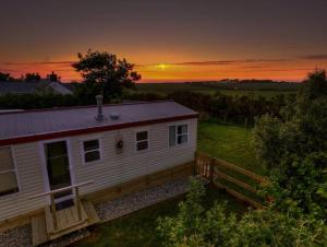 a small white house with a sunset in the background at Helyg Bach in Pwllheli
