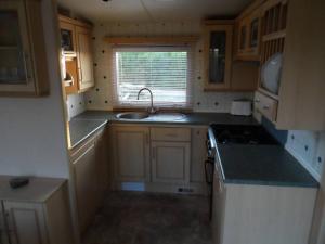a kitchen with wooden cabinets and a sink and a window at Helyg Bach in Pwllheli