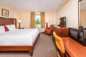 a hotel room with a bed and a flat screen tv at Days Inn & Suites by Wyndham Lake Okeechobee in Okeechobee