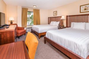 a hotel room with two beds and a desk at Days Inn & Suites by Wyndham Lake Okeechobee in Okeechobee