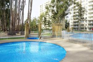 una gran piscina azul con una valla metálica en Hermoso y nuevo departamento en Algarrobo Norte, en Algarrobo