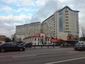 基輔的住宿－Gloria park apartment，停车场内停放汽车的大型建筑