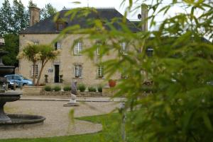 a large stone house with a fountain in front of it at Domaine Utah Beach - Le Grand Hard in Sainte-Marie-du-Mont