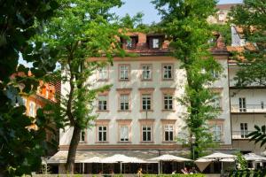 een groot wit gebouw met bomen ervoor bij Julija&Robert's Riverview Apartments and Rooms in Ljubljana