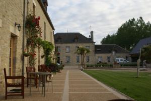 a courtyard with a table and chairs and a building at Domaine Utah Beach - Le Grand Hard in Sainte-Marie-du-Mont