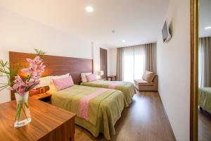 Cette chambre comprend 2 lits et une table fleurie. dans l'établissement Hotel Nossa Senhora da Paz, à Fátima 30 autres photos