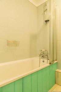 a bathroom with a bath tub with green and white tiles at Seafront Apartment with Garden in Brighton & Hove +19 photos