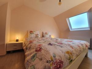 a bedroom with a bed with a floral bedspread and a window at Alix in Zuienkerke