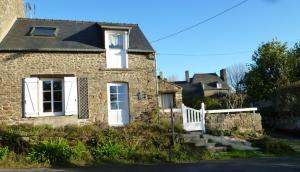 une maison en pierre avec une porte blanche et des escaliers. dans l'établissement GIVERNY COTTAGE, à Saint-Coulomb