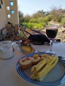 einen Teller mit Essen und ein Glas Wein auf dem Tisch in der Unterkunft Cabaña Nachitor in San Pedro de Atacama