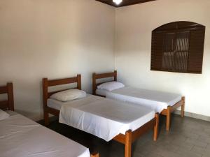 a room with two beds and a window in it at Hotel Bem Bom in Campo Verde