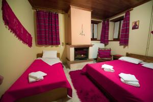 two beds in a room with red sheets and a fireplace at To Petrino Guesthouse in Agios Germanos