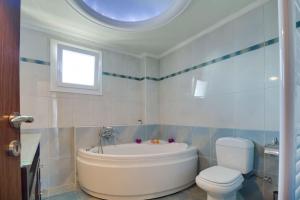 a bathroom with a tub and a toilet and a window at Villa Natali in Flogita