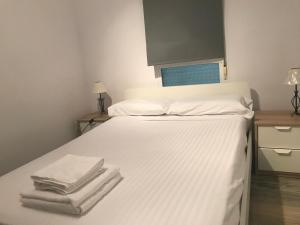 Una cama blanca con toallas encima. en Ático Port La Ràpita, en Sant Carles de la Ràpita