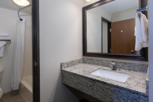 a bathroom with a sink, mirror, and towel rack at AmericInn by Wyndham Iron River in Iron River