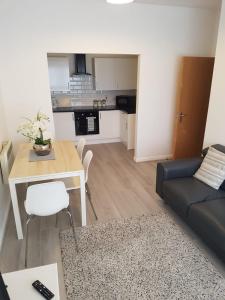 ein Wohnzimmer mit einem Sofa und einem Tisch sowie eine Küche in der Unterkunft Lynn's Liverpool Apartment in Liverpool
