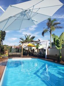 a large swimming pool with an umbrella and a pool at Recanto Rustico Itapoá in Itapoa