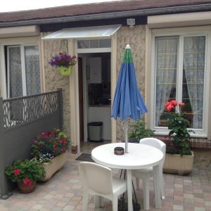 een tafel en stoelen en een parasol op een patio bij Au Bon Gite - Studio in Arromanches-les-Bains